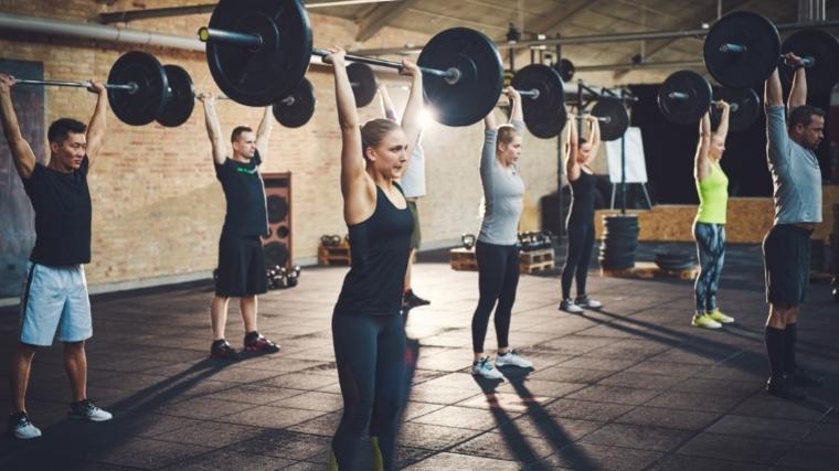 A roup of people performing overhead barbell presses