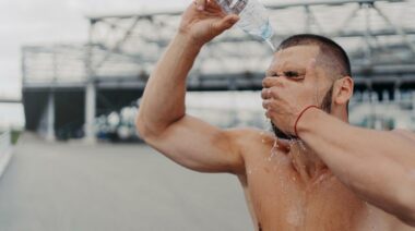 A fit an pouring water on his face from a water bottle