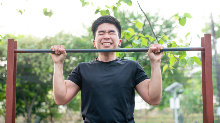 Man straining while performing pull-ups