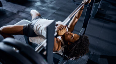 Muscular woman in gym performing bench press