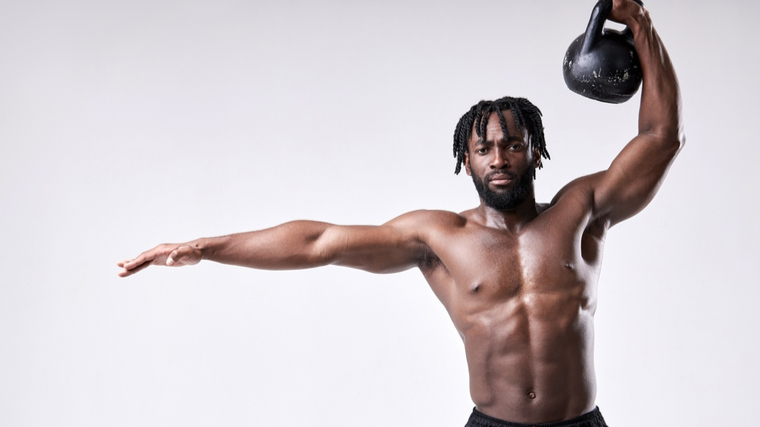 Muscular man pressing kettlebell overhead