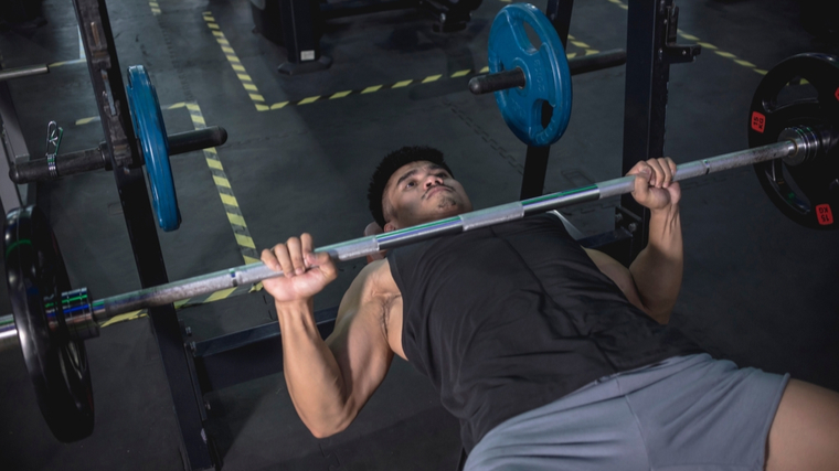 Man holding barbell on chest performing bench press