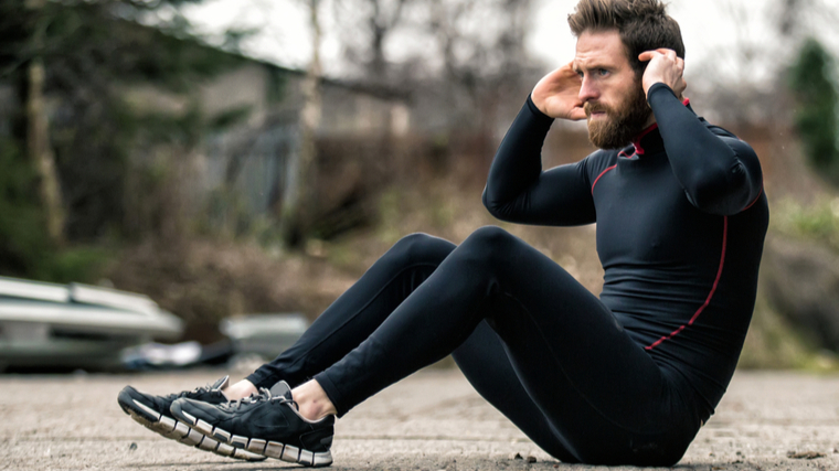 Man outdoors performing sit-up exercise