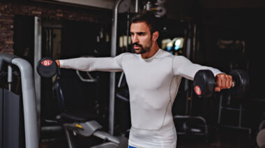 Muscular man performing dumbbell lateral raise