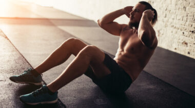 Shirtless man performing sit-up exercise