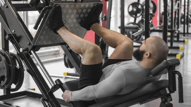 Bald man in gym on leg press machine