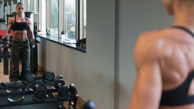 Muscular woman in gym performing dumbbell curl