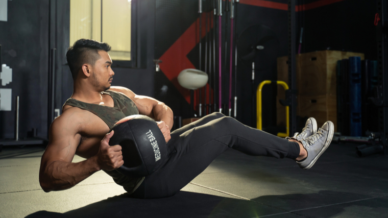 Man performing ab exercise with medicine ball