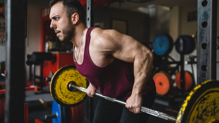 Muscular man performing barbell row exercise