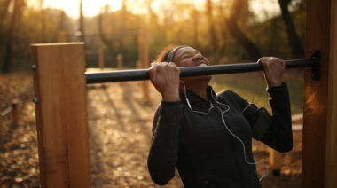 person outside doing chin-ups at sunrise