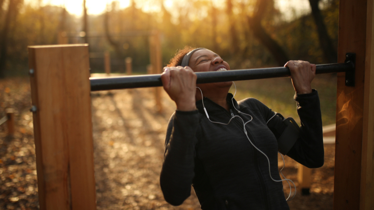 person outside doing chin-ups at sunrise