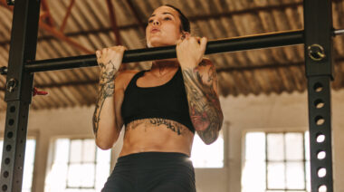 tattooed woman performing chin-ups