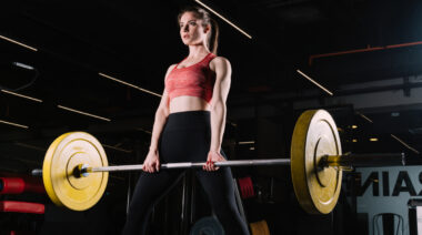 long-haired person in gym performing sumo deadlift