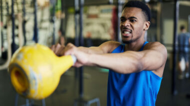 person straining while performing kettlebell exercise