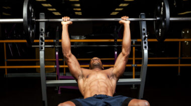 muscular person in gym performing barbell press