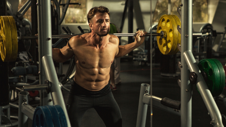 muscular person performing barbell squat in gym