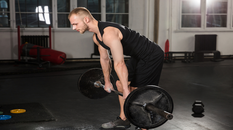 person in gym bent forward holding barbell