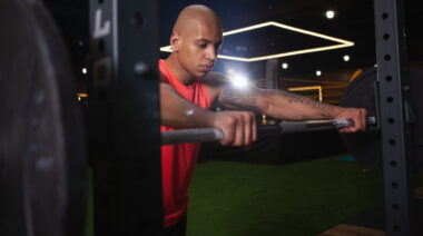 bald person preparing to lift barbell