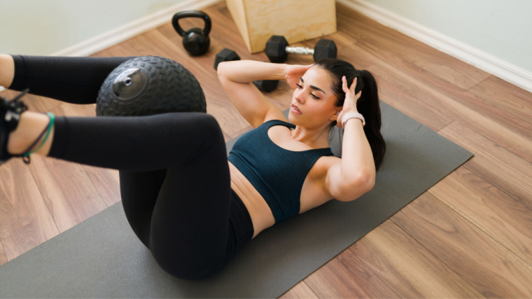 person on floor doing medicine ball ab exercise