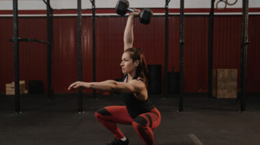 person in gym doing dumbbell squat