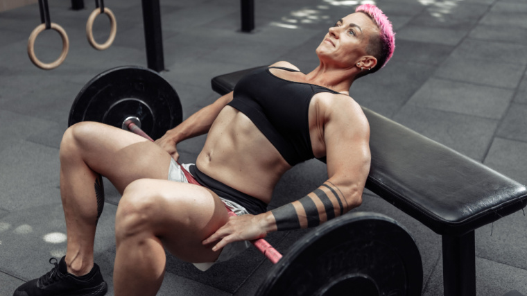 person in gym performing hip thrust on flat bench