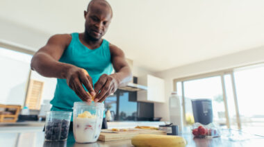 Bald person in kitchen making smoothie