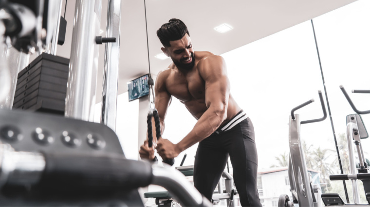 muscular person in gym doing cable exercise