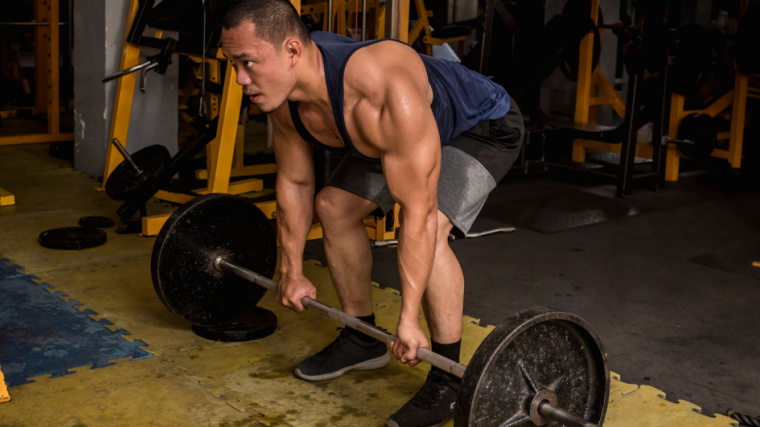 muscular bodybuilder in gym doing barbell deadlift