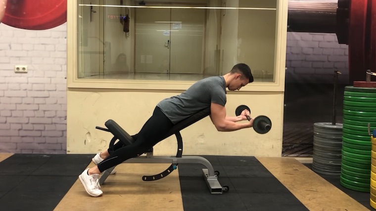 person in gym on bench curling barbell