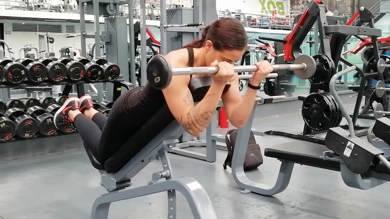 person in gym curling barbel on bench