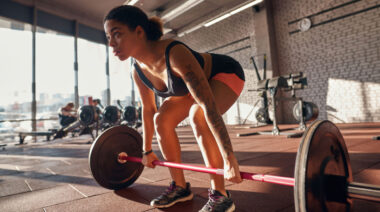 person in gym doing barbell deadlift