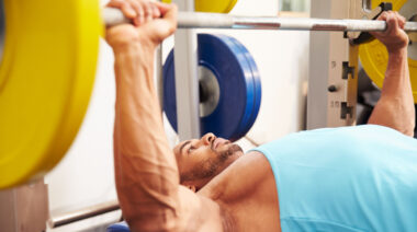 muscular person in gym doing bench press