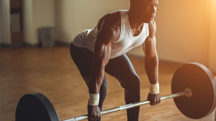 Muscular person performing barbell deadlift