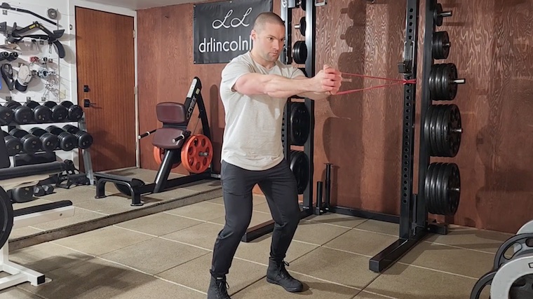 Dr. Merrick Lincoln in gym doing resistance band ab exercise.