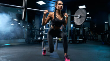 Long-haired person in gym doing lunge exercise