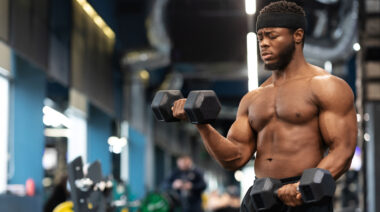 Muscular person in gym doing dumbbell curls