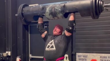 Strongman Mitchell Hooper in gym pressing weight overhead