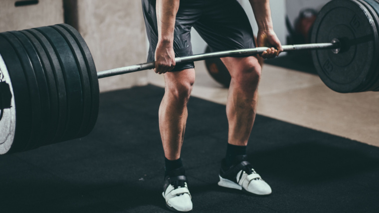 Person in gym deadlifting heavy barbell