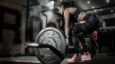 Person in gym performing barbell deadlift