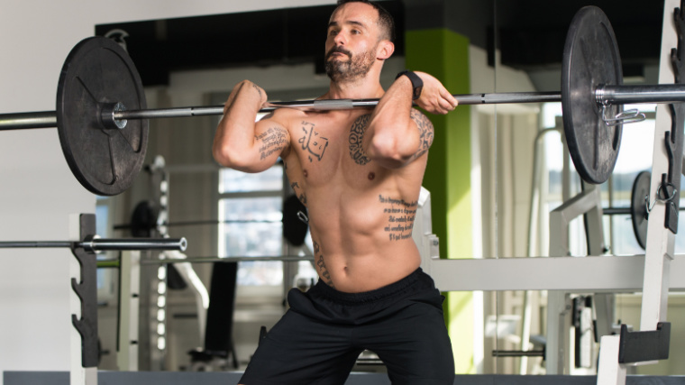 Muscular person in gym doing barbell front squat