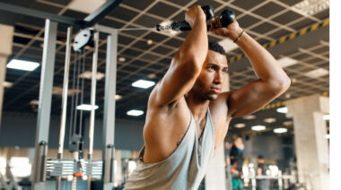 Muscular person in gym going cable triceps exercise