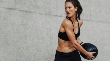 Long-haired person doing medicine ball exercise outdoors