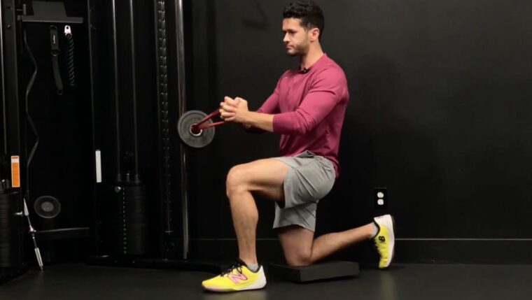 Coach James Shapiro performing kneeling Pallof press with resistance band and weight