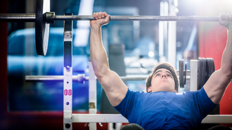 muscular person in gym performing incline barbell bench press