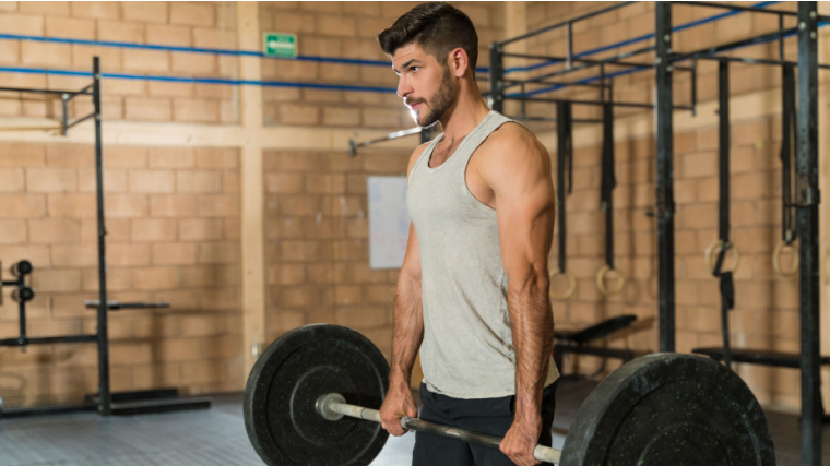 Person in gym doing barbell deadlift