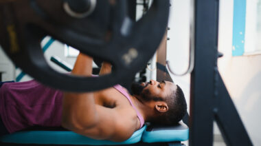 Person in gym doing barbell bench press