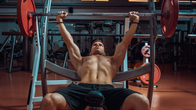 Muscular person in gym doing incline barbell bench press