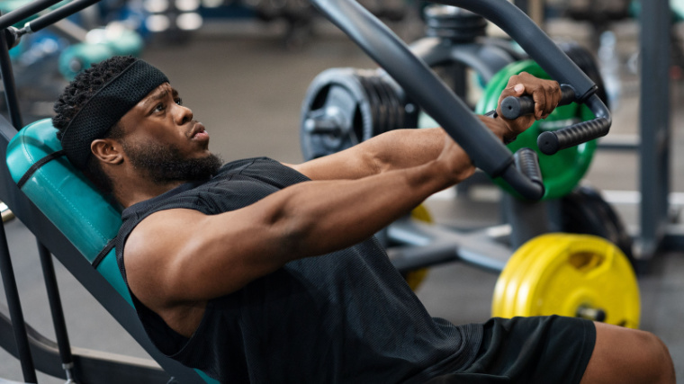 muscular person in gym performing machine chest press