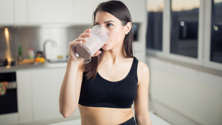 Long-haired person in kitchen drinking shake