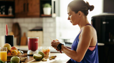 Long-haired person in gym cutting fruit for smoothie